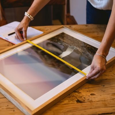 Person Measuring a Picture Frame Using Tape Measure